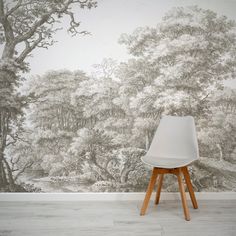 a white chair sitting in front of a wall with a forest mural on it's side