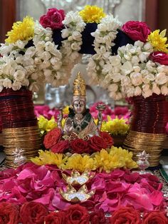 there is a statue surrounded by flowers and vases on the table in front of it