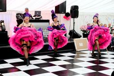 two women in pink dresses are dancing on a black and white checkered floor