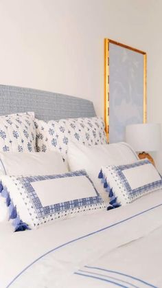 a bed with blue and white pillows on it's headboard in a bedroom