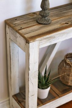 a small wooden shelf with a potted plant on top and a wicker basket underneath