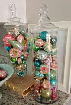 two glass jars filled with ornaments on top of a counter