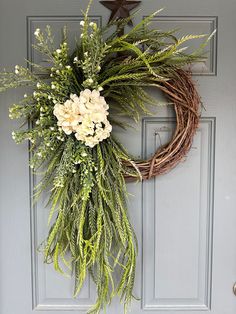 a wreath with white flowers and greenery hangs on the front door's blue door