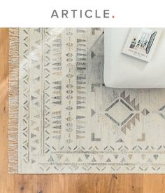 a white couch sitting on top of a wooden floor next to a rug with an arrow pattern