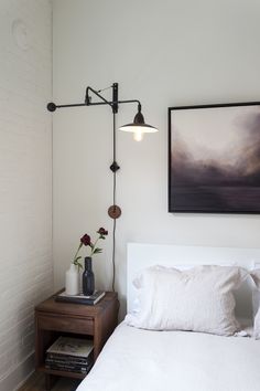 a bedroom with a bed, nightstand and painting on the wall