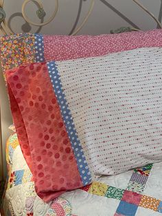 a close up of a bed with a quilt and pillows on it's headboard