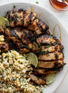 grilled chicken, corn and limes on a white plate