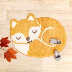 a rug with a sleeping fox on it next to an autumn maple leaf and shoes