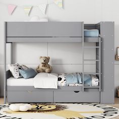 a gray bunk bed with two drawers and a teddy bear sitting on the bottom shelf