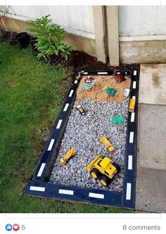 a toy construction truck is in the middle of a graveled area with grass and rocks