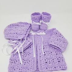 a crocheted baby outfit and booties are laying next to each other