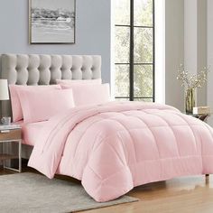a bed with pink comforter and pillows in a room