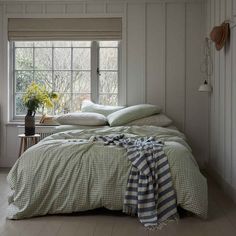 a bed sitting in a bedroom next to a window with a blanket on top of it