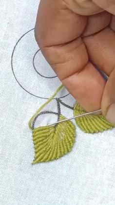 someone is stitching leaves on a piece of fabric