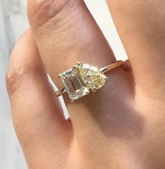 a woman's hand holding an engagement ring with two diamonds on it and the center diamond