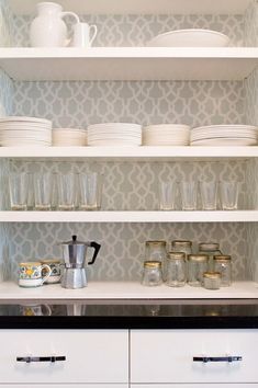 the shelves in this kitchen are filled with dishes and cups