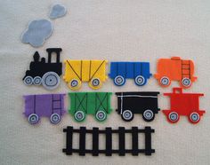 there are many different colored toy trains on the white blanketed tablecloth with clouds above them