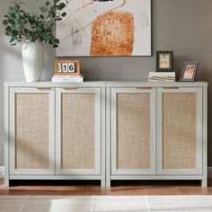 a white sideboard with two doors and some pictures on the wall next to it