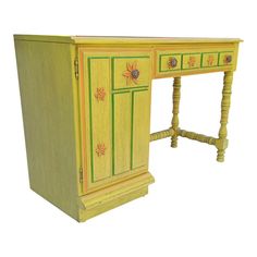 an old desk painted yellow and green with flowers on the top, sitting in front of a white background
