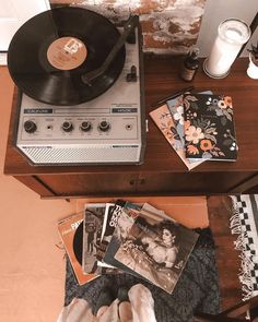 a record player sitting on top of a wooden table next to a pile of records