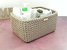 a basket with soap, lotion and other items in it on a pink surface