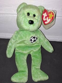 a green teddy bear with a soccer ball on it's chest and tag in its ear