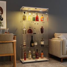 a display case filled with liquor bottles on top of a table next to a couch