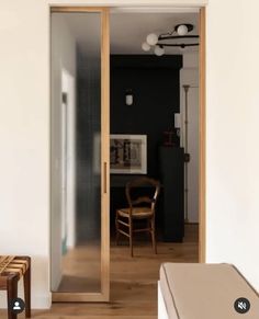 an open door leading into a room with wooden floors and white walls, along with two chairs