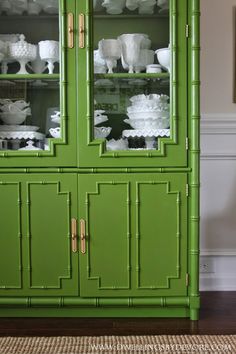 a green china cabinet with glass doors