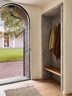 an open door leading to a courtyard with a bench and coat rack on the wall