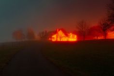 a house is lit up at night on a foggy day in the country side
