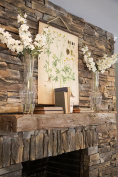 some flowers are in vases on a mantel above a fire place with an old book