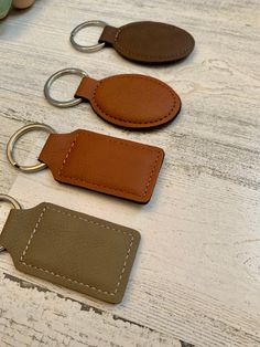 three leather key fobs sitting on top of a wooden table