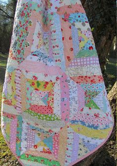 a quilt hanging from a tree in the woods