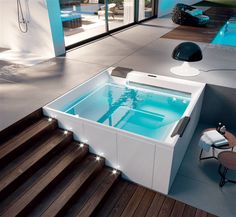 an indoor jacuzzi tub in the middle of a room with stairs leading up to it