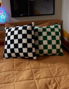 two black and white pillows sitting on top of a bed next to a neon sign