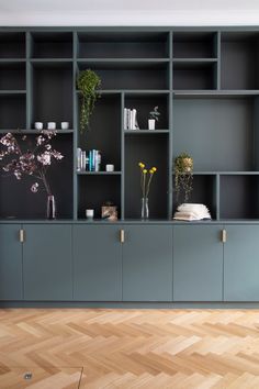 a living room with grey bookcases and wooden flooring on the side wall