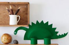 there is a green dinosaur on the shelf