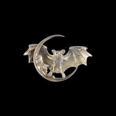 a silver brooch with a bat on it