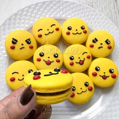 a white plate topped with yellow macaroons covered in emoticions and smiling faces