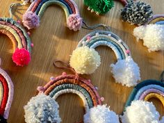 many different colored pom poms on a wooden table next to scissors and thread