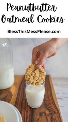 a hand holding a cookie over a glass of milk