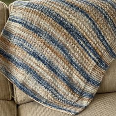 a close up of a couch with a striped blanket on it's back end