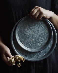 a person holding a metal plate with flowers in it's palm and two hands