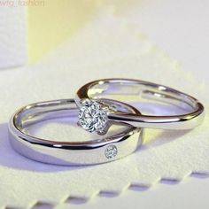 two white gold wedding rings with diamond accents on each one and the other side, sitting next to each other