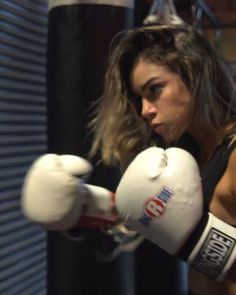 a woman wearing boxing gloves in a gym