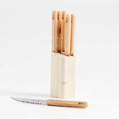 four wooden utensils in a holder next to a small knife on a white background