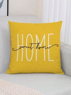 a yellow pillow sitting on top of a white couch next to a wall with the words home