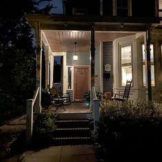 a porch at night with rocking chairs on the front and steps leading up to it