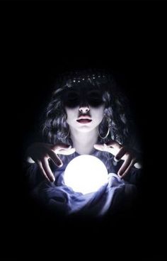 a woman holding a glowing ball in her hands, with the light shining on her face